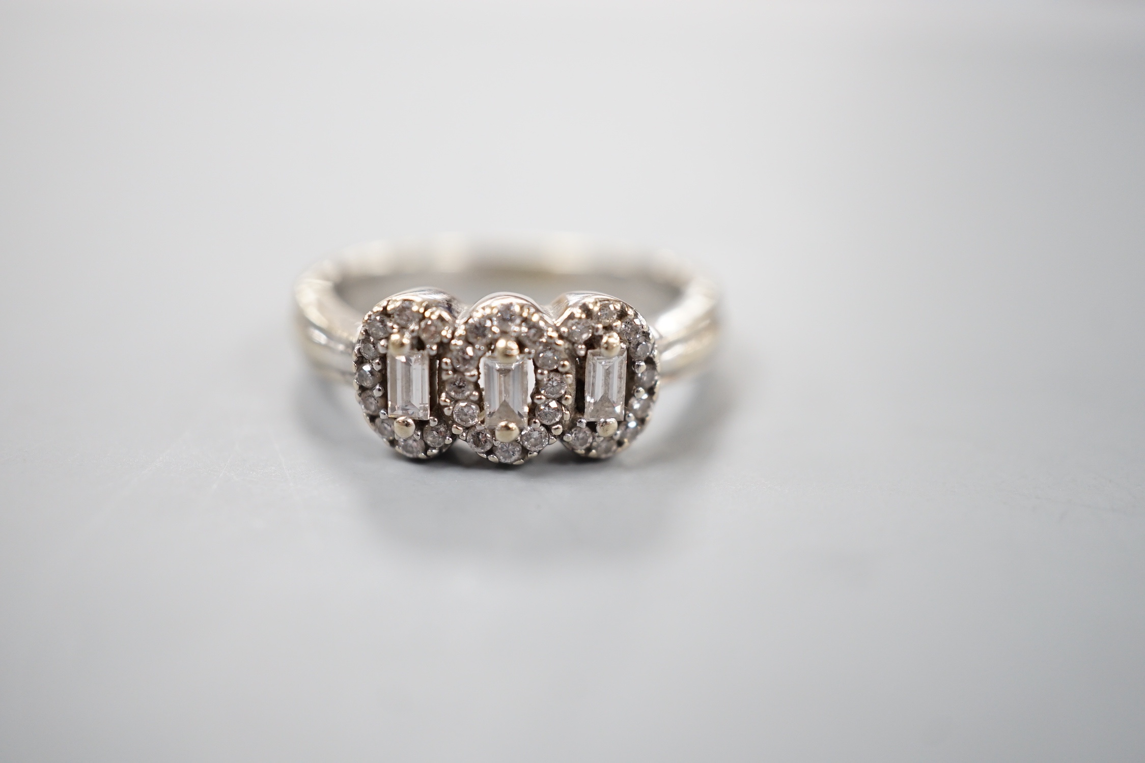 A modern 18ct white gold and diamond set triple cluster ring, size L, gross weight 5.3 grams.